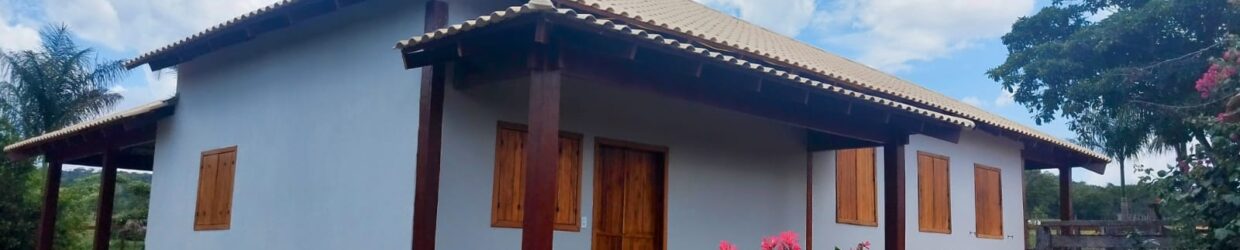 Casa residencial concluída pela STYL Construtora, com fachada clara, varanda e paisagismo